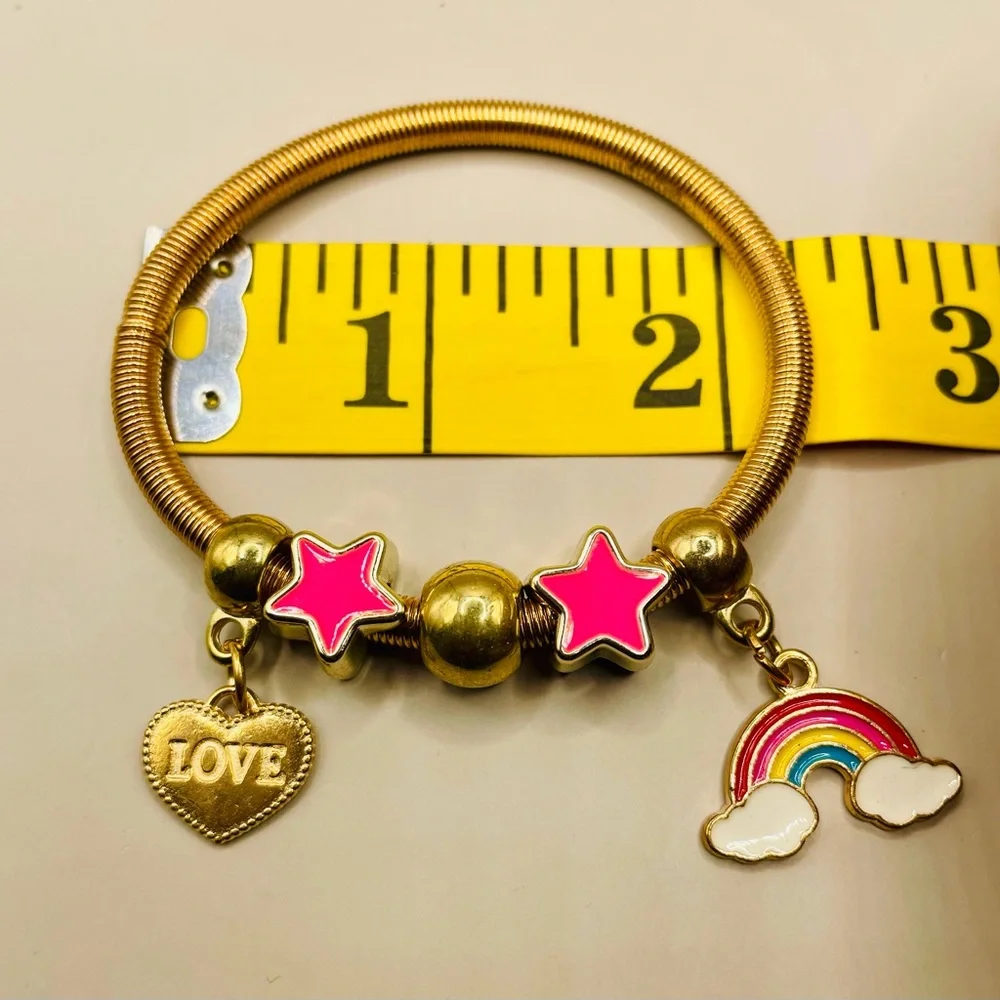 Yellow gold plated spring baby bangle with rainbow, heart and star charms.